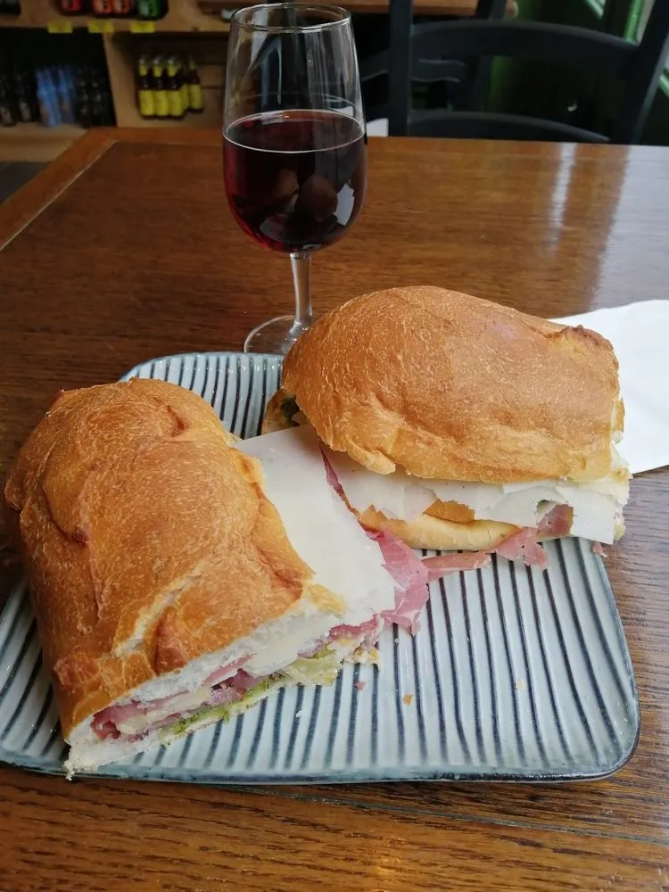 Panino coupé en deux sur une assiette, avec un verre de vin rouge